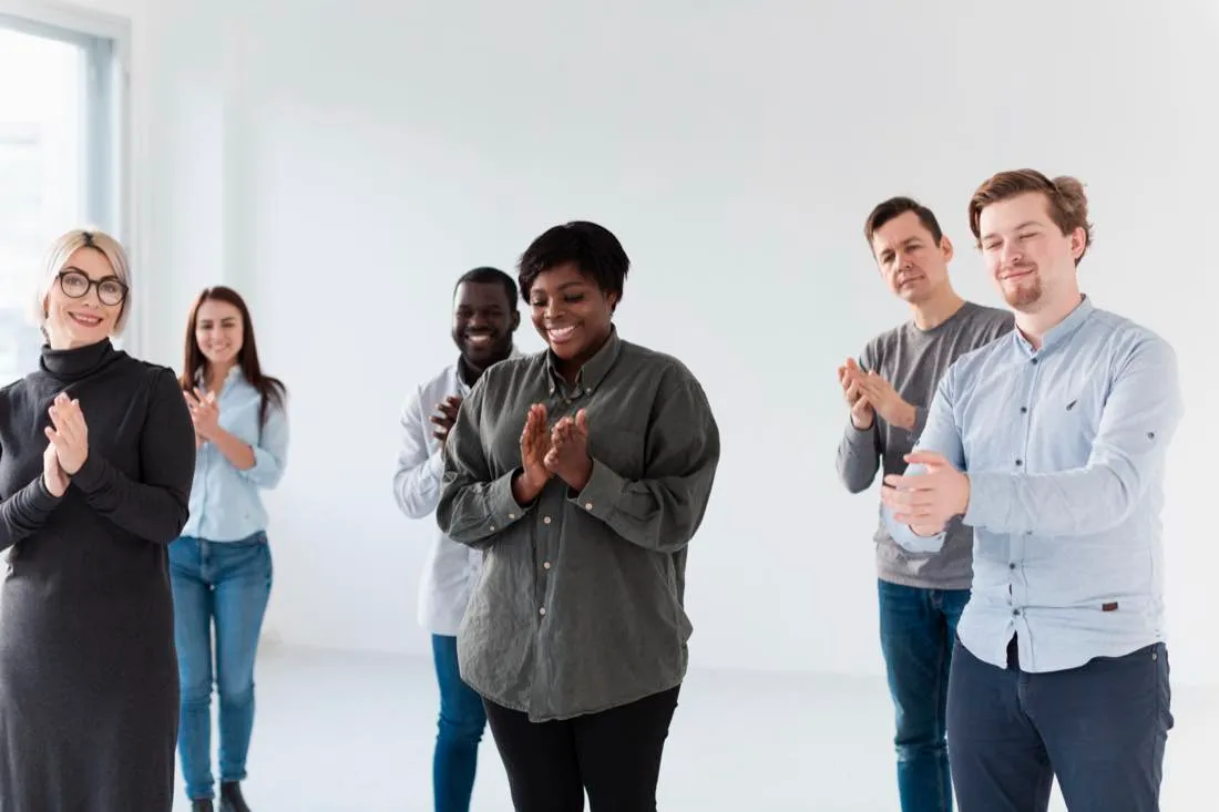 Sechs Menschen applaudieren in einem hellen Raum